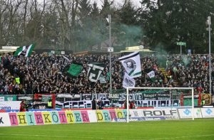 Die vollbesetzte Fiffi-Gerritzen-Kurve, Heimat der Münsteraner Ultras und benannt nach Felix „Fiffi“ Gerritzen, der 1951 mit dem SC Preußen im Finale um die Deutsche Meisterschaft stand. – CC BY-NC 2.0: Groundhopping Merseburg, „Preußen Münster v Dynamo Dresden, https://www.flickr.com/photos/fchmksfkcb/15804486984/in/album-72157650189620307/